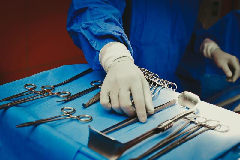 Close-up of hand holding surgical instruments in the operating room, Surgical tools lying on the table