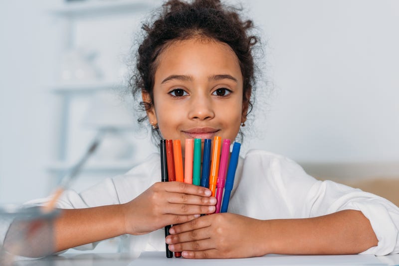 A Black girl holding markers.