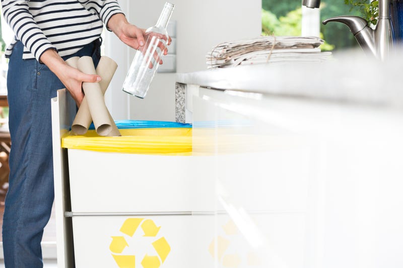 A woman recycles paper towel tubes and a glass bottle