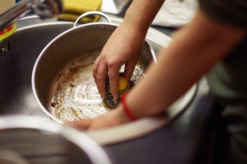 Someone scrubs a dirty pot in a dish