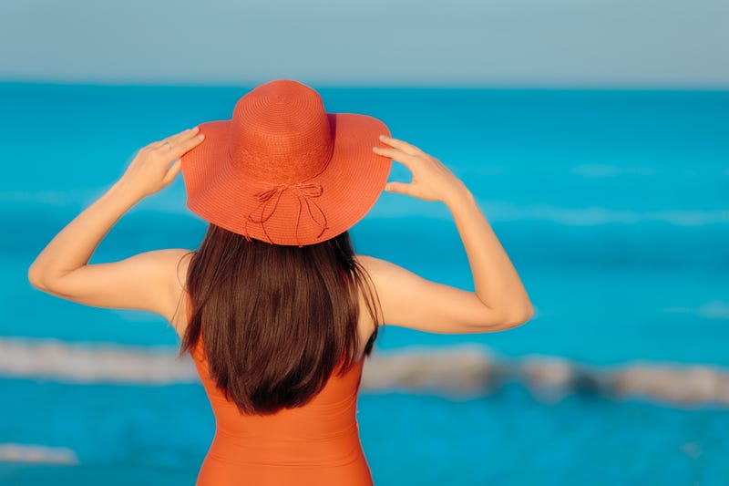 sunbathing woman in hat looking at the sea