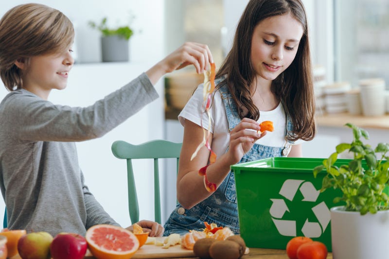 kids adding food scraps to a compost bin