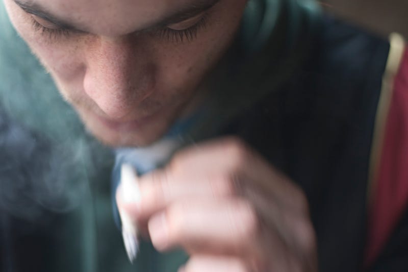 A young person smokes a marijuana joint.