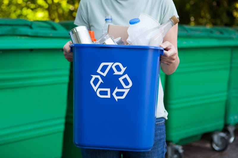 A person holding a recycling bin filled with items