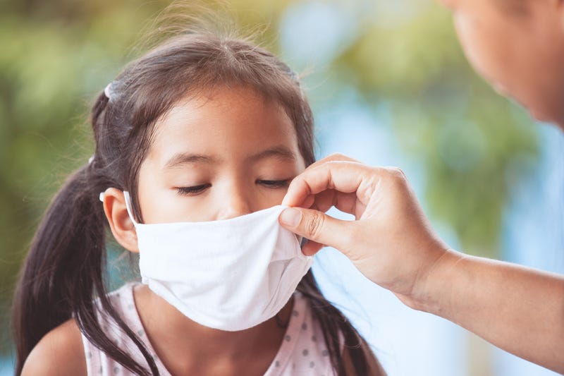 parent helps daughter put on face mask