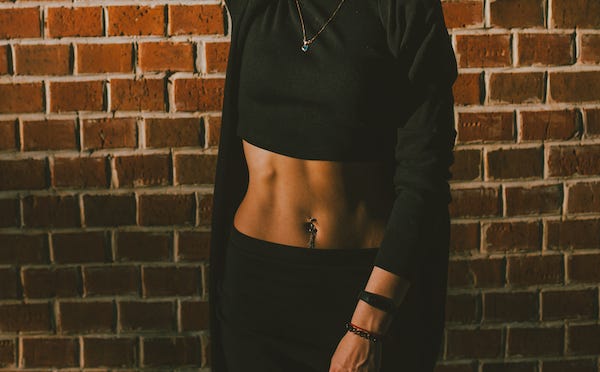Woman in a crop top standing against a brick wall