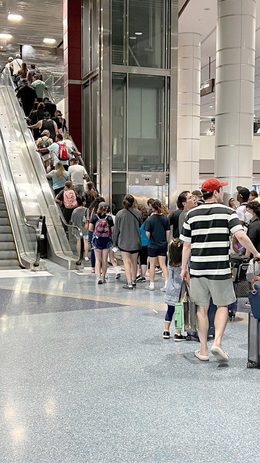 Passengers wait to take an escalator to their gate at Reid International