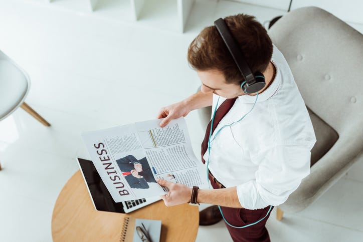 guy with headphones on reading the newspaper