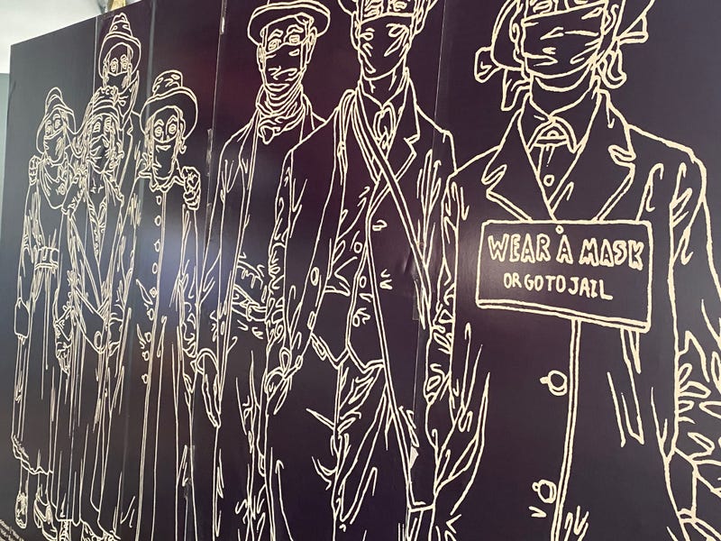 A mural painted over a boarded-up San Francisco storefront during the COVID-19 pandemic implores city residents to "wear a mask or go to jail."