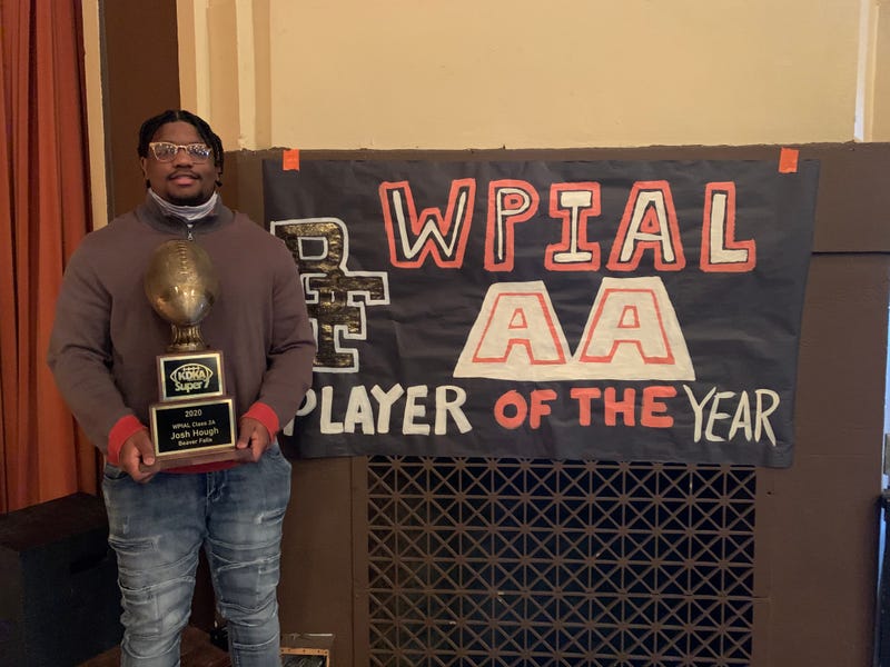 Josh Hough poses with his KDKA Radio Super 7 trophy in front of a banner inside Beaver Falls High School.
