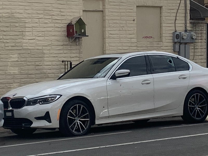 A white BMW belonging to a 28-year-old man who survived dozens of gunshots with only an ankle wound. The car was hit nearly 20 times on the driver's side.