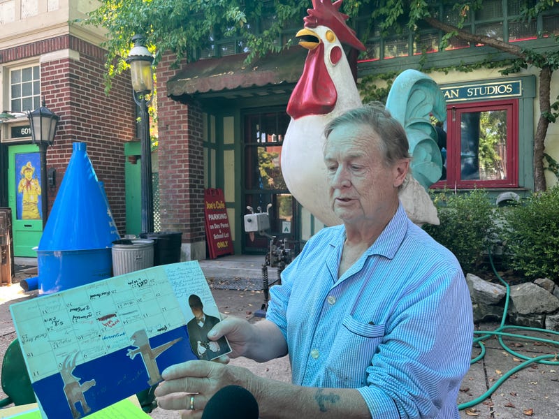 Bill Christman sits holding a collage