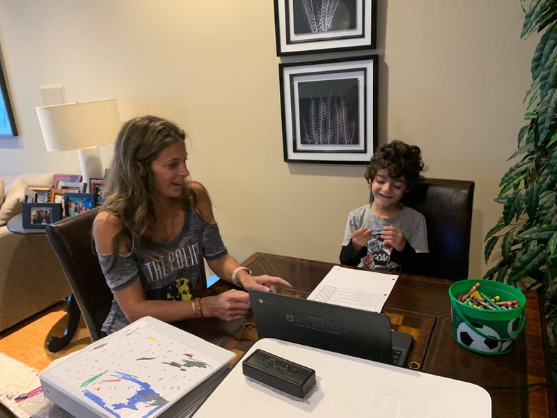 Jill Jacobson helps her kindergartner, Logan, at home in the living room.