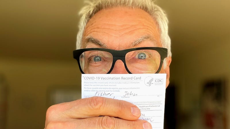 John holding his vaccination card