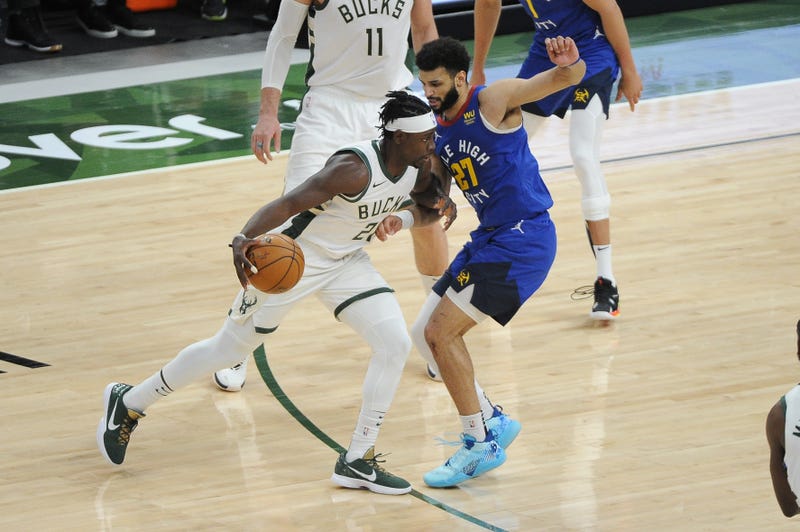 Mar 2, 2021; Milwaukee, Wisconsin, USA; Milwaukee Bucks guard Jrue Holiday (21) dribbles the ball against Denver Nuggets guard Jamal Murray (27) in the second quarter at Fiserv Forum. Mandatory Credit: Michael McLoone-USA TODAY Sports