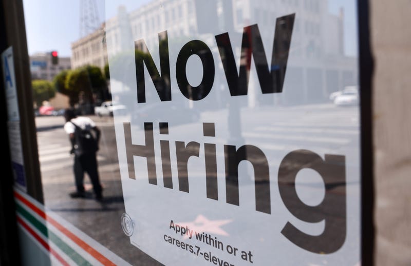 A sign in the window of a business advertises for new employees