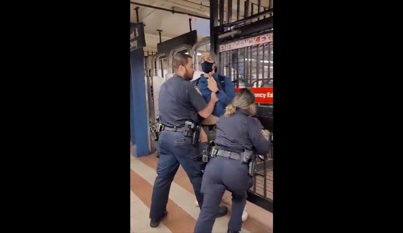 NYPD officers pushing the rider out of the subway station.