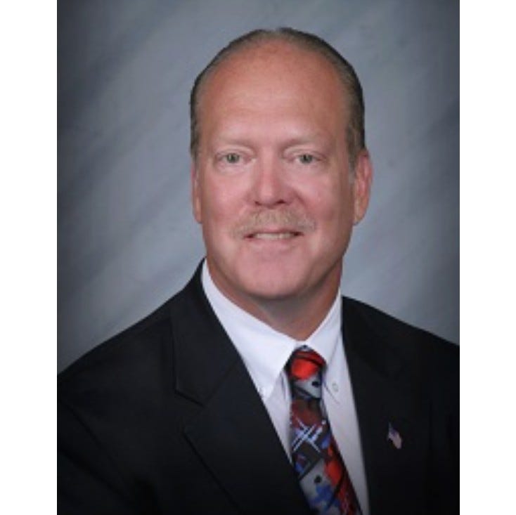 Older white man wearing a suit smiling for camera