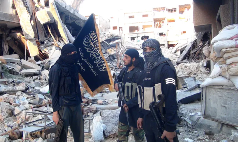 Fighters from the al-Qaida group in the Levant, Al-Nusra Front, stand among destroyed buildings near the front line with Syrian government solders in Yarmuk Palestinian refugee camp, south of Damascus on September 22, 2014.