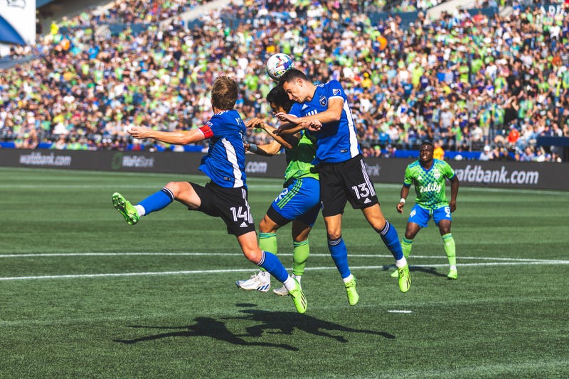 Soccer players go up for a header at Lumen Field