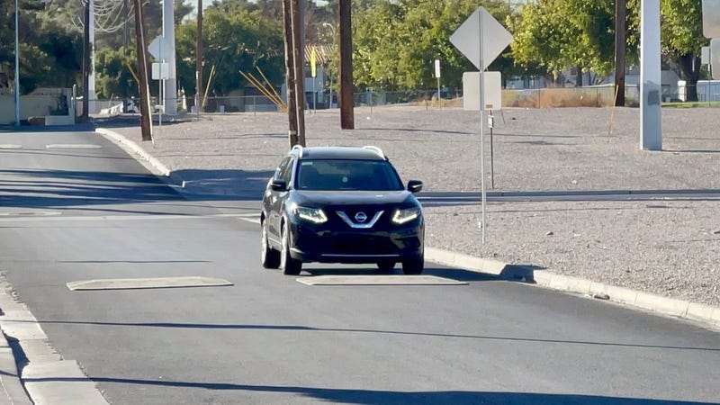 A car goes over speed cushions on a valley road