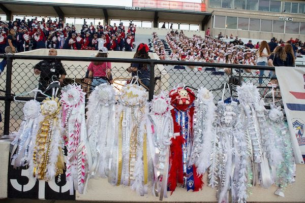 Mums hanging on fence at football game