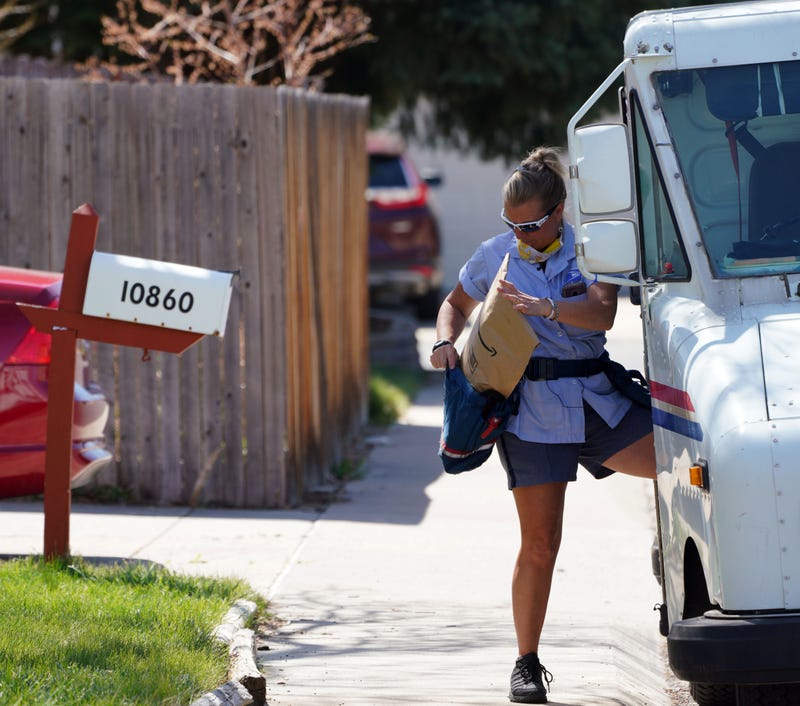 USPS carrierloads mail into her delivery pouch.