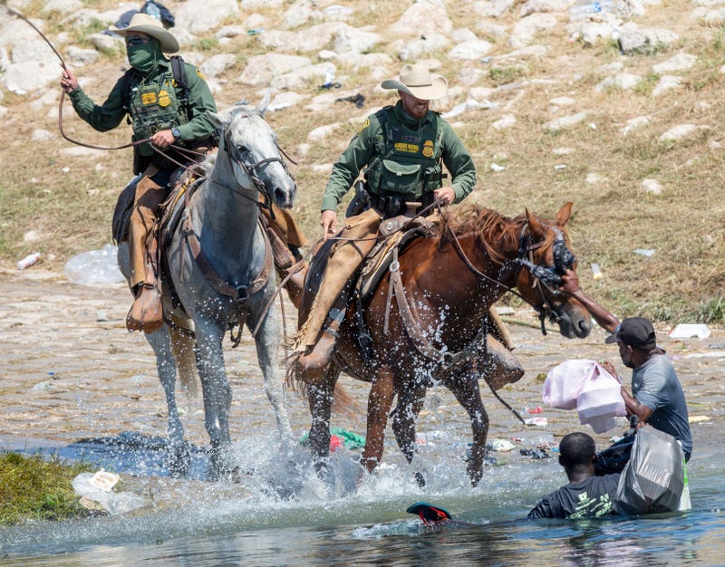 U.S. Border Patrol agents deter Haitians from returning to the U.S. on the bank of the Rio Grande after migrants crossed back to Mexico for food and water.