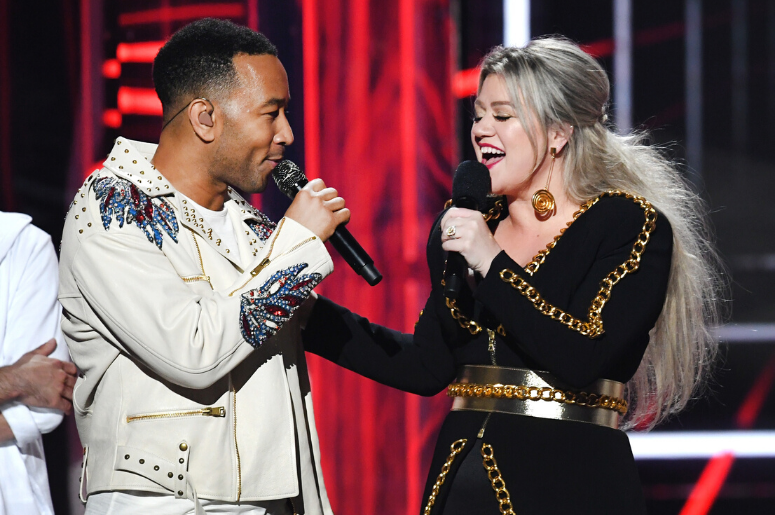 John Legend (L) and host Kelly Clarkson speak onstage during the 2018 Billboard Music Awards