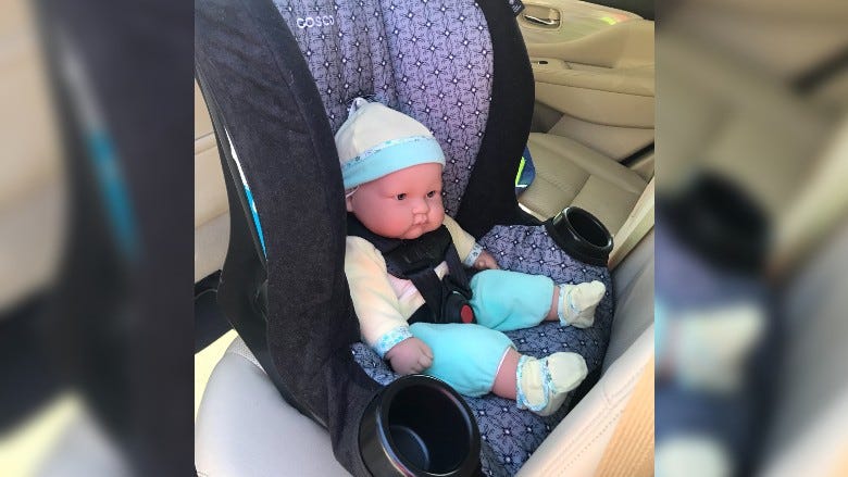 A baby doll in a rear facing car seat in vehicle