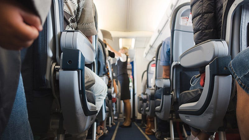 Flight attendant down the aisle of crowded plane