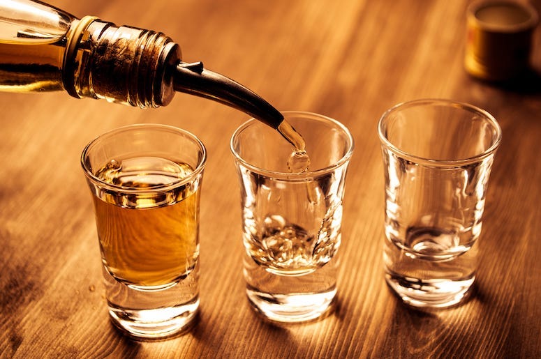 Shots of alcohol are being poured into shot glasses.