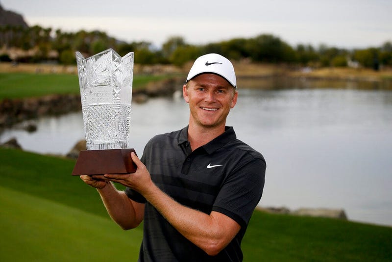 Adam Long holds the trophy on the 18th green after winning the Desert Classic golf tournament on the Stadium Course at PGA West on Sunday
