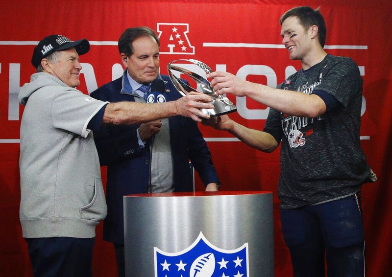New England Patriots head coach Bill Belichick, left, hands off the championship trophy to quarterback Tom Brady after defeating the Kansas City Chiefs in the AFC Championship NFL football game