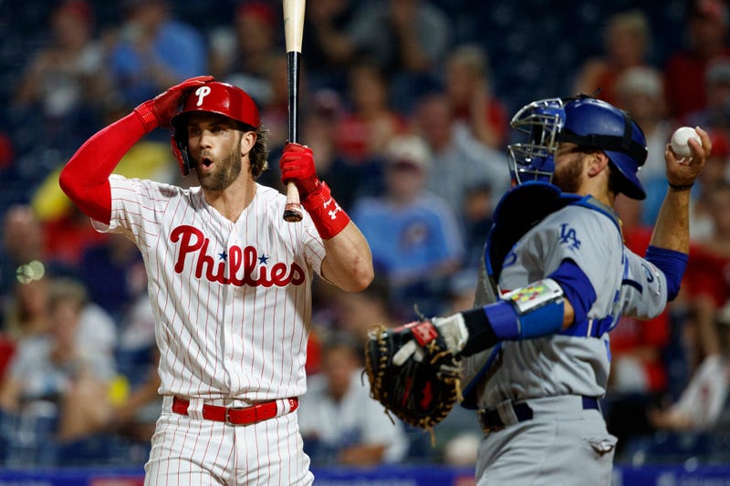 Philadelphia Phillies' Bryce Harper, left, reacts after striking out against Los Angeles Dodgers relief pitcher Julio Urias during the fourth inning of a baseball game Wednesday, July 17, 2019, in Philadelphia.