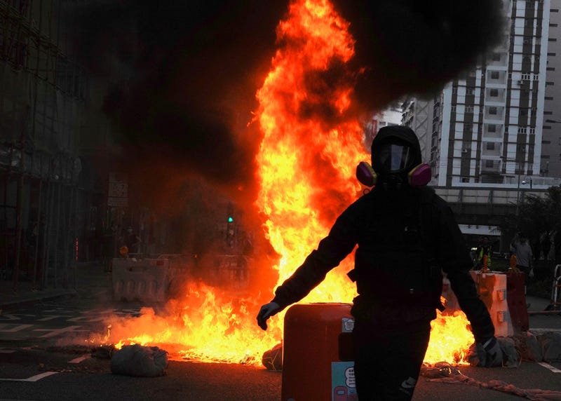 Protestors set fire on a street to prevent police from approaching in Hong Kong, Sunday, Oct. 20, 2019.