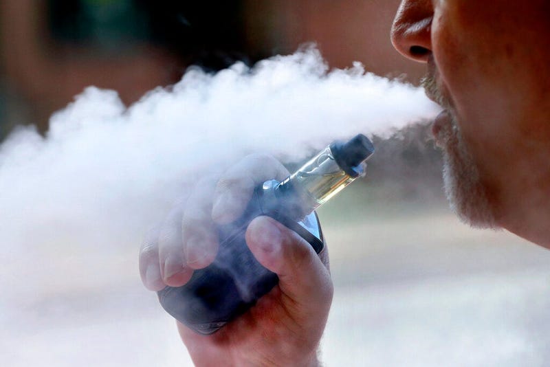 a man exhales while smoking an e-cigarette