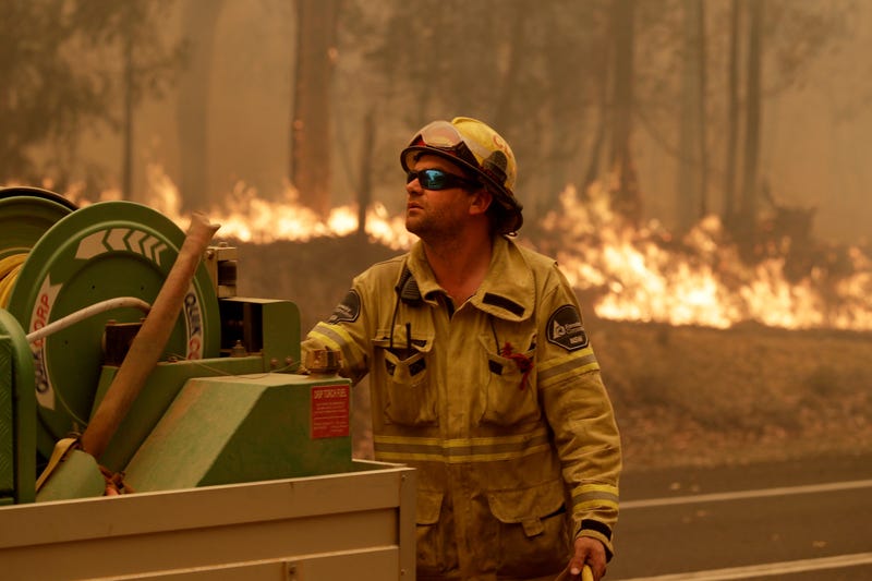 A Forest Corporation worker manages a fire hose as he battles a fire near Moruya, Australia, Saturday.