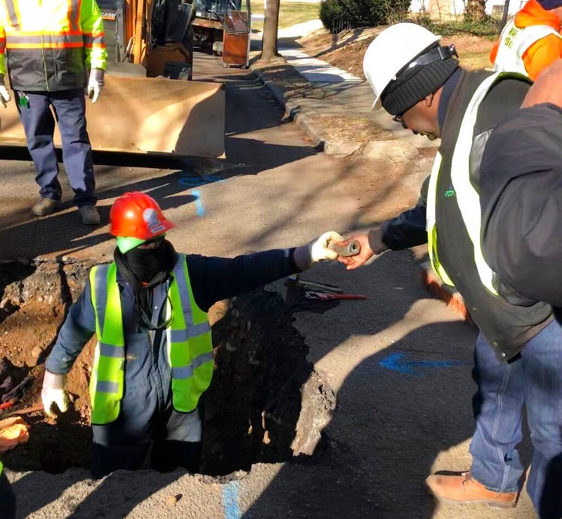 A worker hands a piece of lead pipe to a colleague as they work to remove water service lines Thursday, Jan. 9, 2020, in Trenton, N.J.