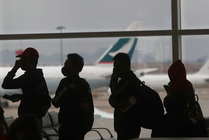 People wearing masks line up for departure at Hong Kong airport in Hong Kong, Tuesday, Feb. 4, 2020. Hong Kong on Tuesday reported its first death from a new virus, a man who had traveled from the mainland city of Wuhan that has been the epicenter of the