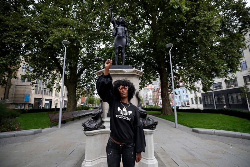 Jen Reid poses for photographs in front of the new black resin and steel statue portraying her, entitled "A Surge of Power (Jen Reid) 2020" by artist Marc Quinn.