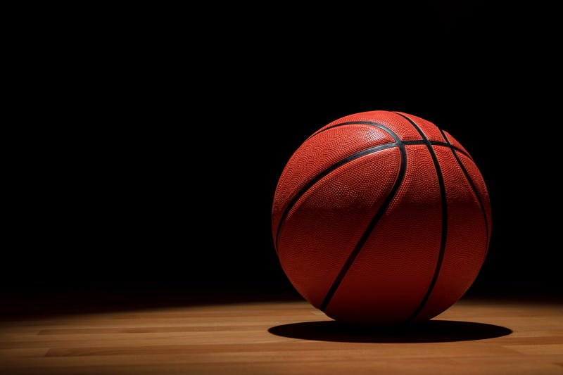 Basketball on wooden court with spotlights from above