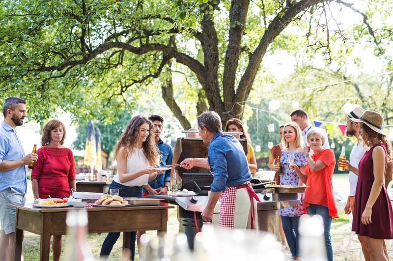 A group gathered around a grill for a bbq