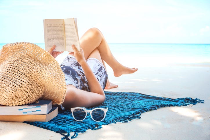 woman sunbathing on beach with belongings around her
