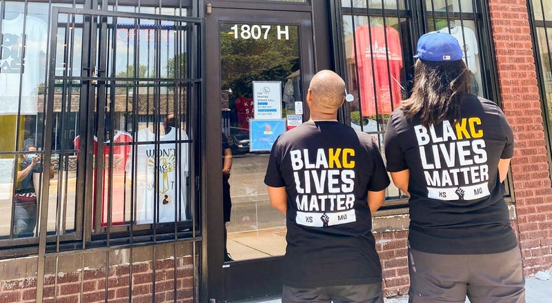 Two men wear a t-shirt that reads 'BlaKC Lives Matter", a twiat on the word 'black'