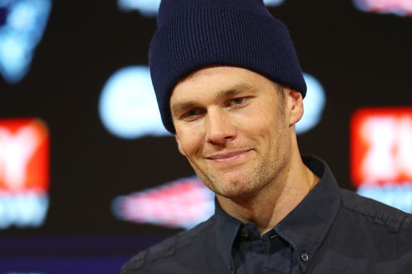 Tom Brady smirks at a press conference with the Patriots.