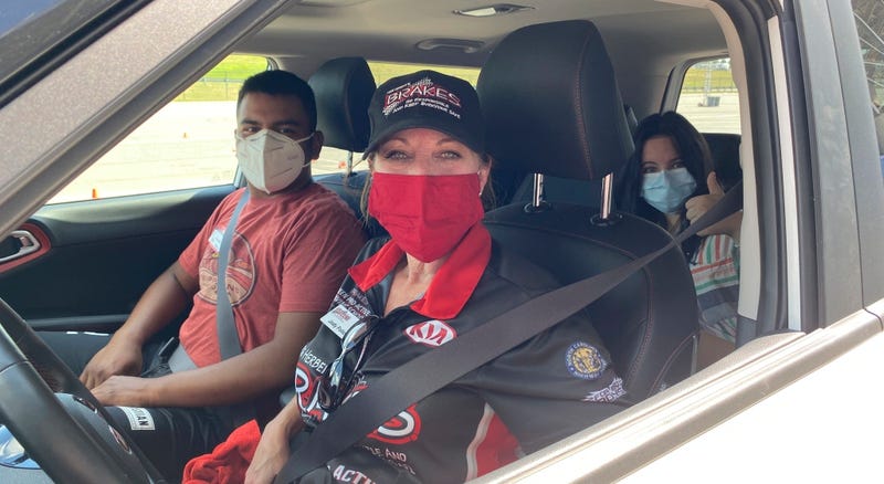 A professional defensive driver sits behind the wheel of a car, with two teens riding as passengers.