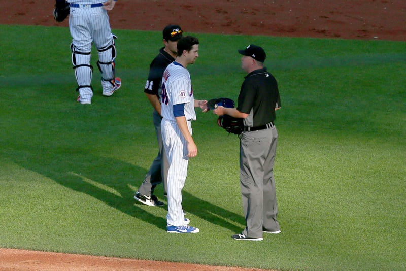 Jun 21, 2021; New York City, New York, USA; Third base umpire Ron Kulpa (46) takes the hat of New York Mets starting pitcher Jacob deGrom (48) to check for foreign substances after the top of the fifth inning against the Atlanta Braves at Citi Field. Mandatory Credit: Brad Penner-USA TODAY Sports