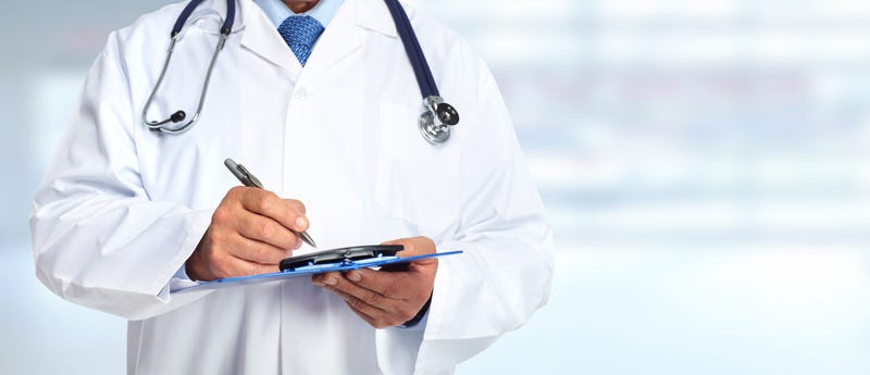 Doctor in white coat holding clipboard