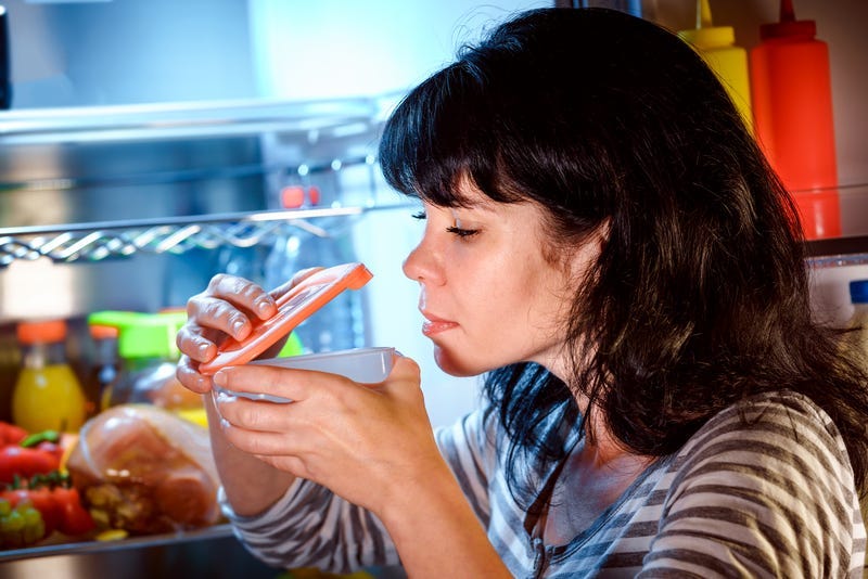Woman sniffing food from fridge